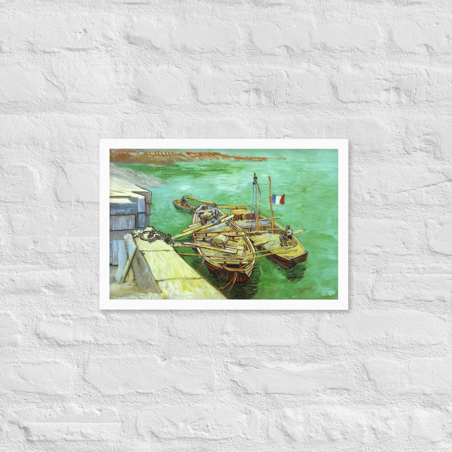 Van Gogh's 'Quay with Men Unloading Sand Barges' on a 12"x18" white framed poster print on a white brick wall.