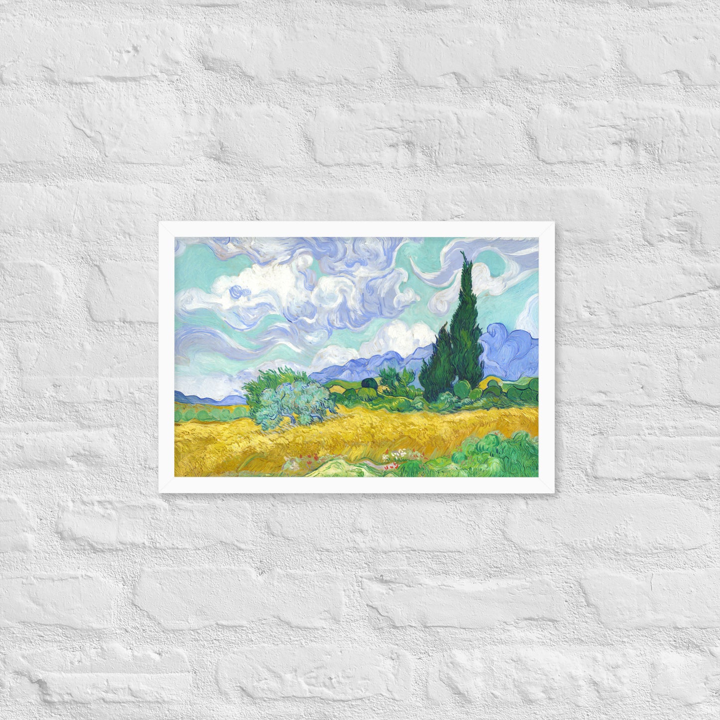 Van Gogh's 'Wheat Field with Cypresses' on a 12"x18" white framed poster print on a white brick wall.