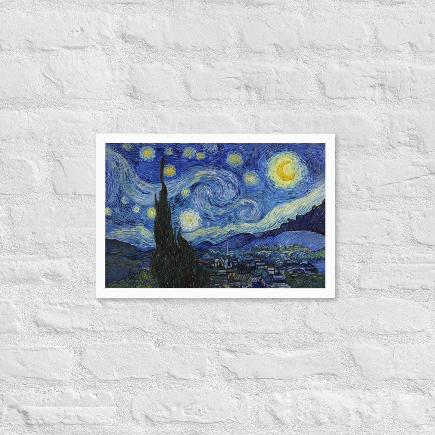 Van Gogh's 'Starry Night' on a 12"x18" white framed poster print on a white brick wall.