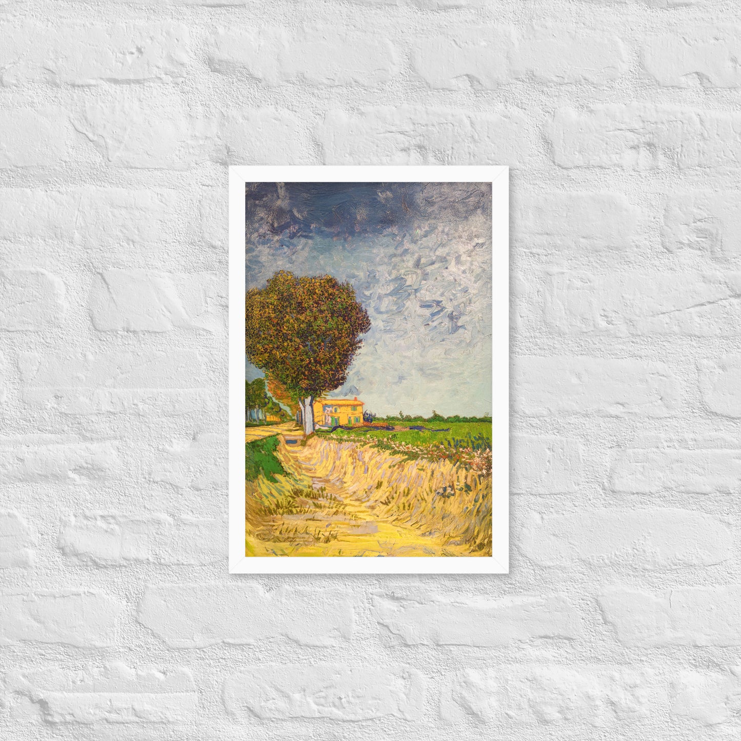 Van Gogh's 'A Lane near Arles' on a 12"x18" white framed poster print on a white brick wall.