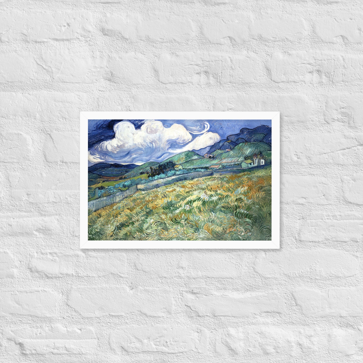 Van Gogh's 'Landscape from Saint-Rémy' on a 12"x18" white framed poster print on a white brick wall.