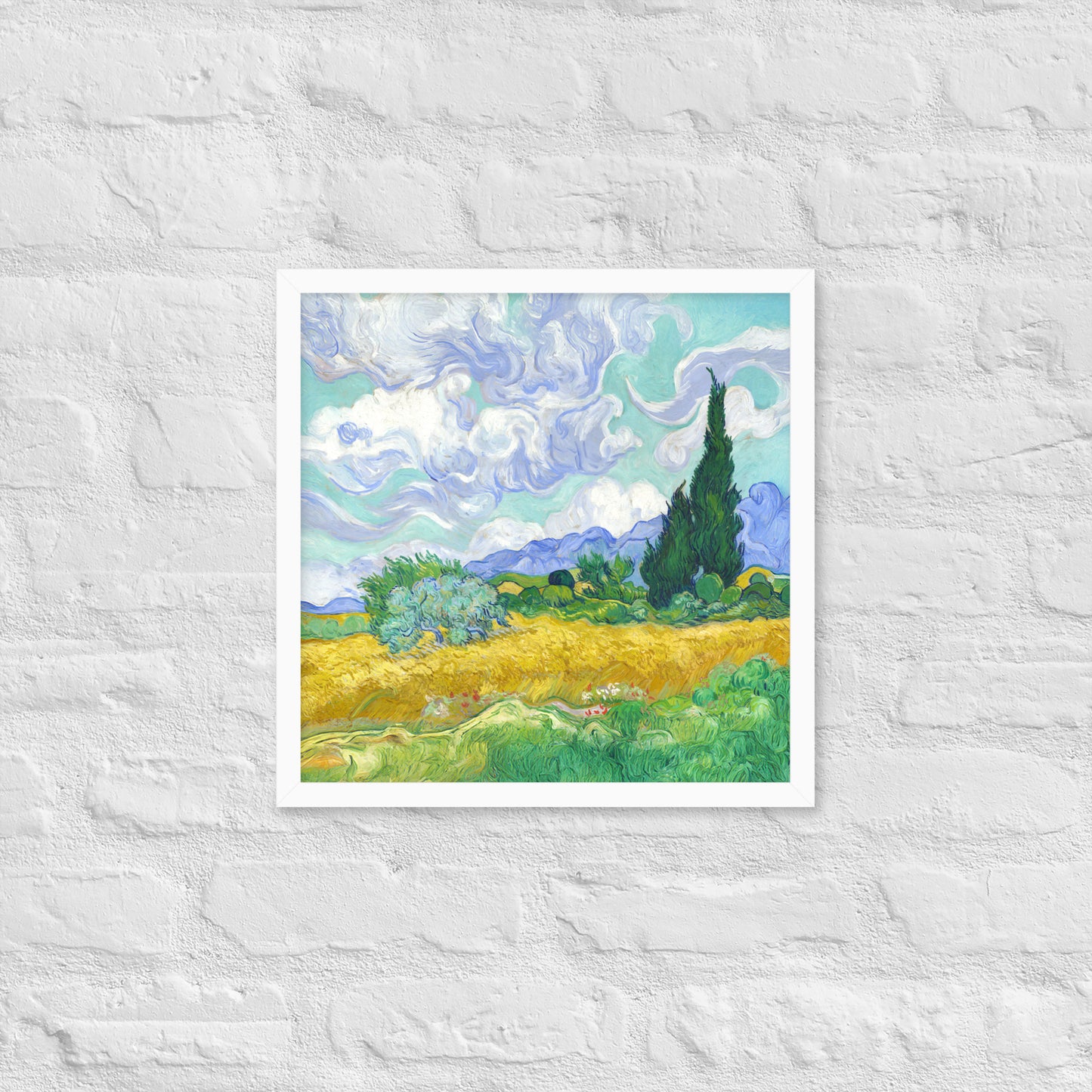 Van Gogh's 'Wheat Field with Cypresses' on a 16"x16" white framed poster print on a white brick wall.