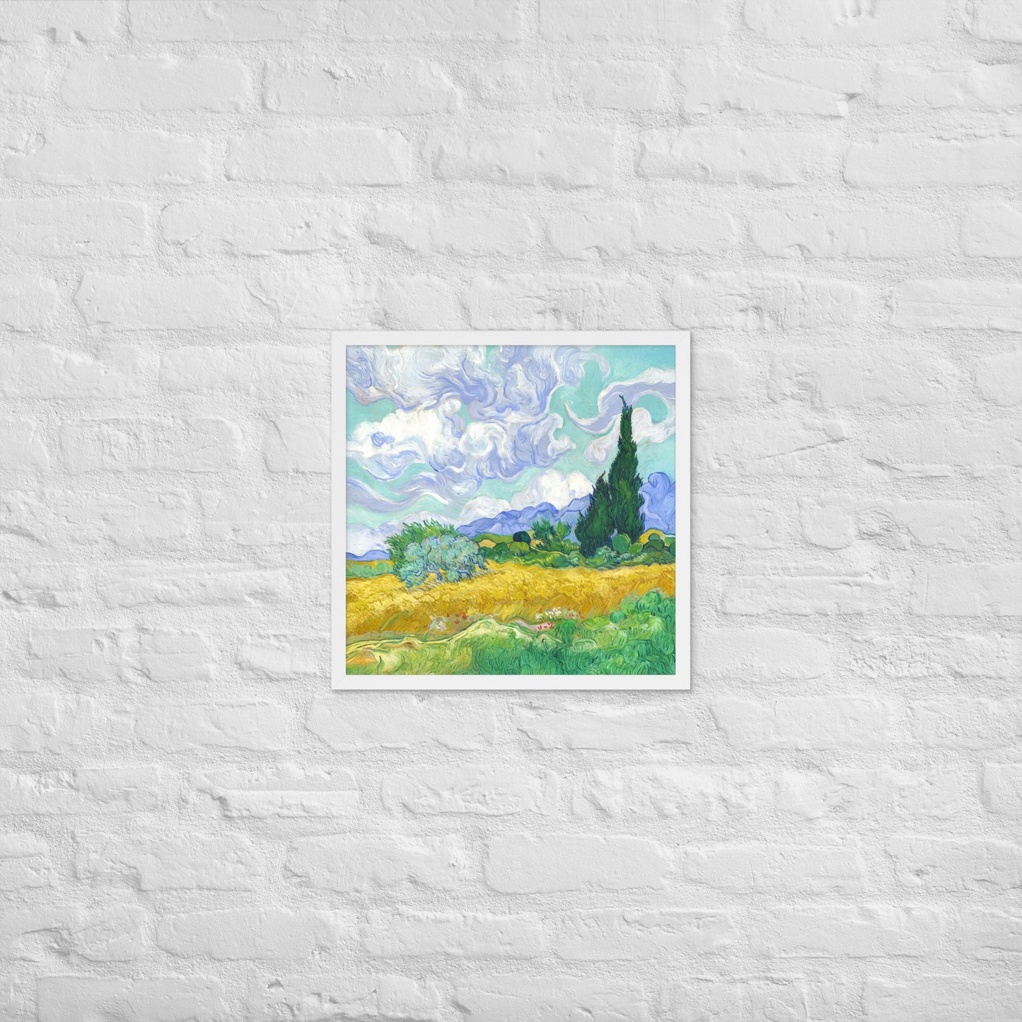 Van Gogh's 'Wheat Field with Cypresses' on a 18"x18" white framed poster print on a white brick wall.