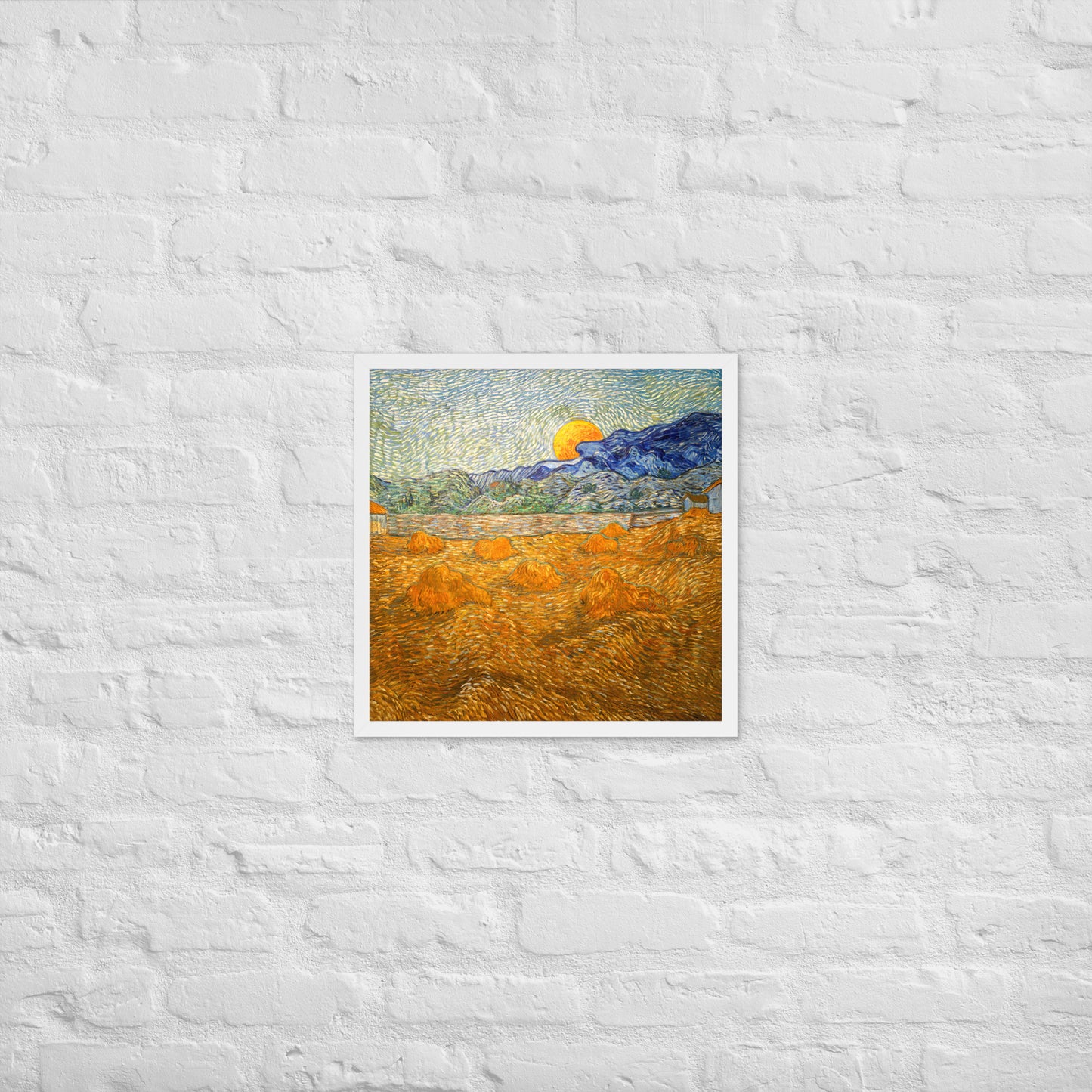 Van Gogh's 'Landscape with Wheat Sheaves and Rising Moon' on a 18"x18" white framed poster print on a white brick wall.