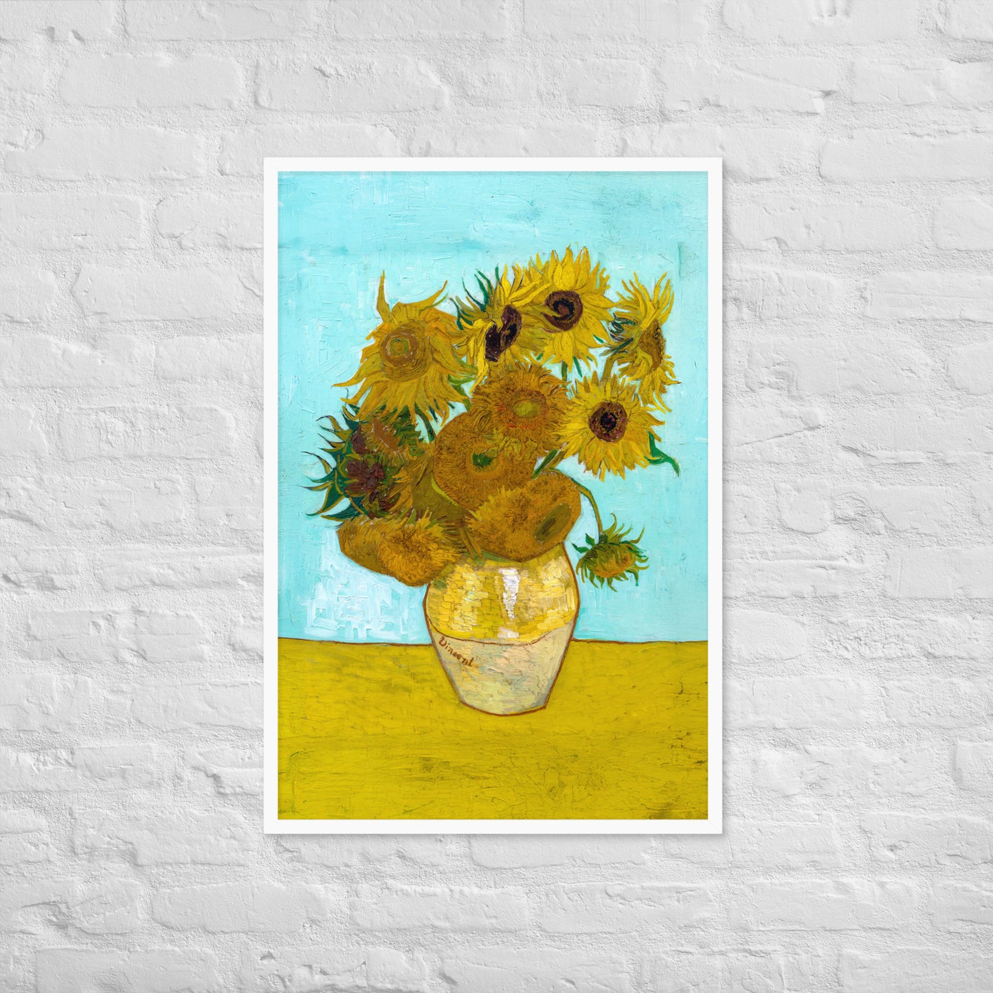 Van Gogh's 'Vase with Twelve Sunflowers' on a 24"x36" white framed poster print on a white brick wall.