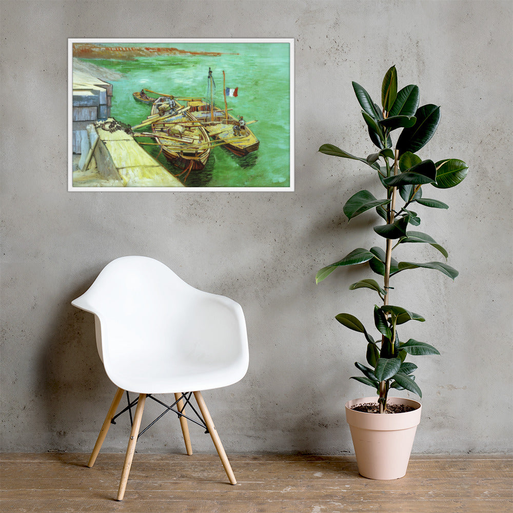Van Gogh's 'Quay with Men Unloading Sand Barges' on a 24"x36" white framed poster print on a light gray concrete wall with a white chair and plant below.