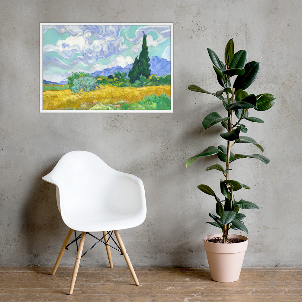 Van Gogh's 'Wheat Field with Cypresses' on a 24"x36" white framed poster print on a light gray concrete wall with a white chair and plant below.