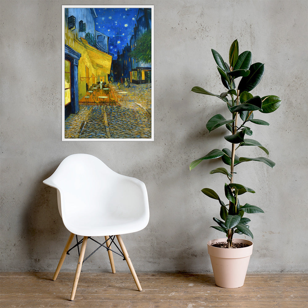 Van Gogh's 'Café Terrace at Night' on a 24"x36" white framed poster print on a light gray concrete wall with a white chair and plant below.