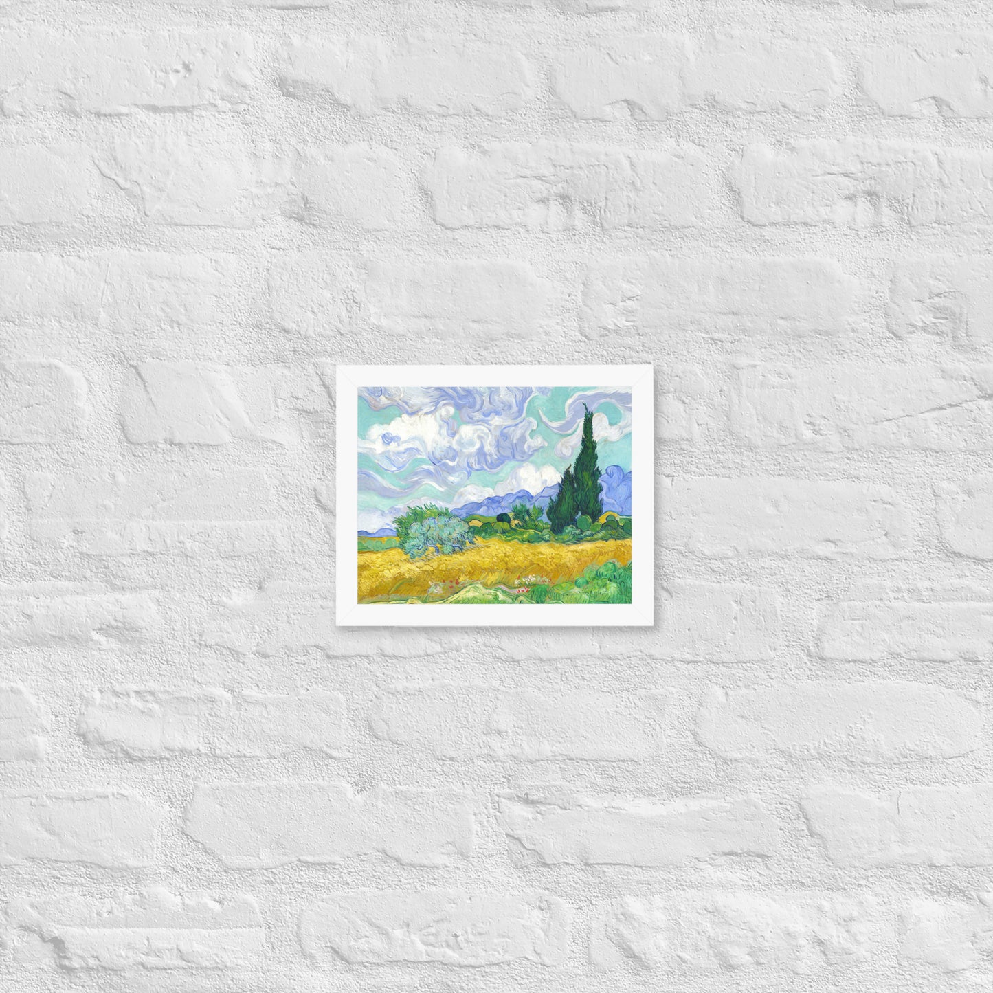 Van Gogh's 'Wheat Field with Cypresses' on a 8"x10" white framed poster print on a white brick wall.