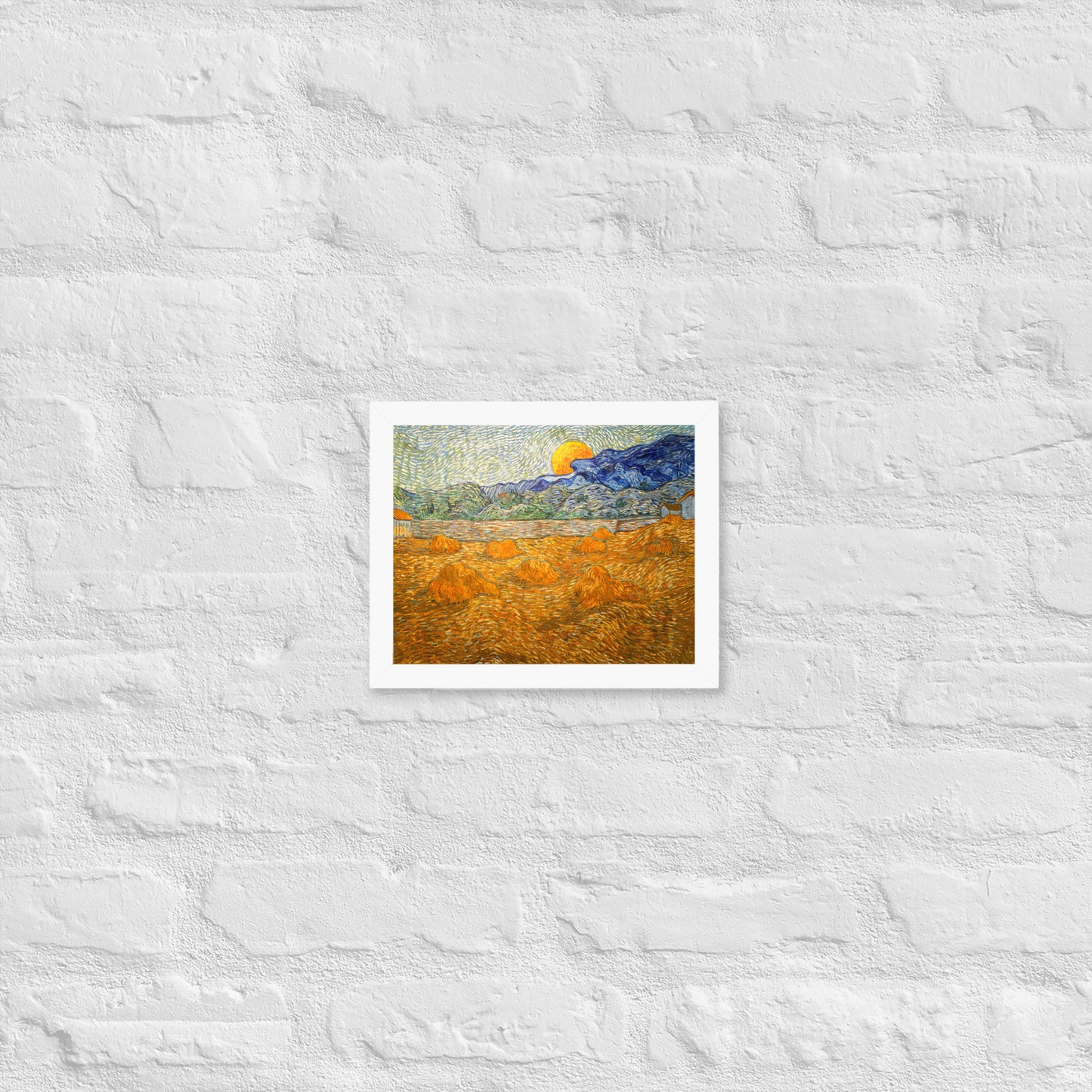 Van Gogh's 'Landscape with Wheat Sheaves and Rising Moon' on a 8"x10" white framed poster print on a white brick wall.