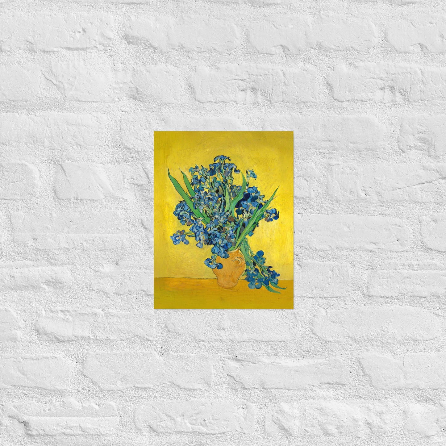 Van Gogh's 'Vase with Irises Against a Yellow Background' on a 11"x14" unframed poster print on a white brick wall.