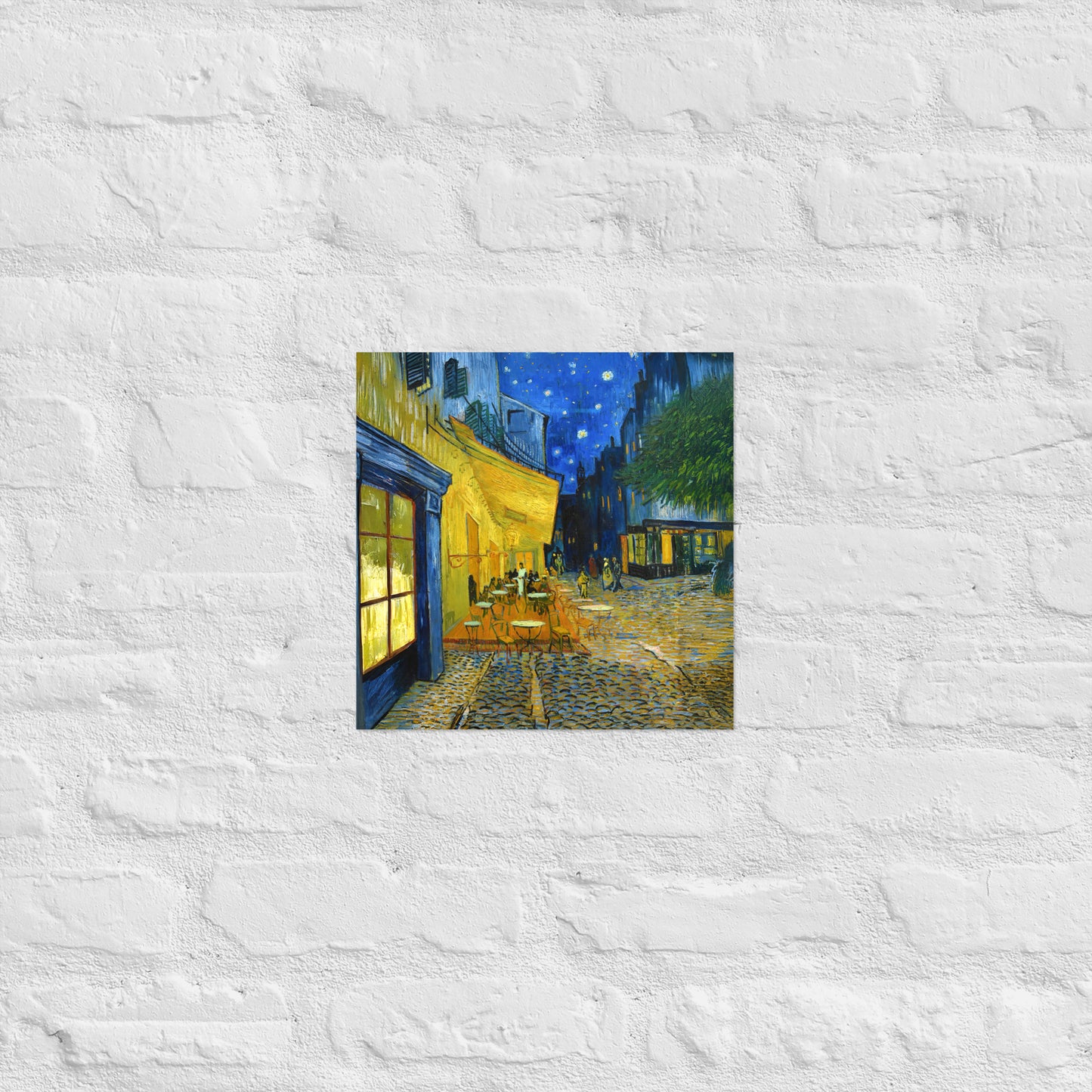 Van Gogh's 'Café Terrace at Night' on a 12"x12" unframed poster print on a white brick wall.
