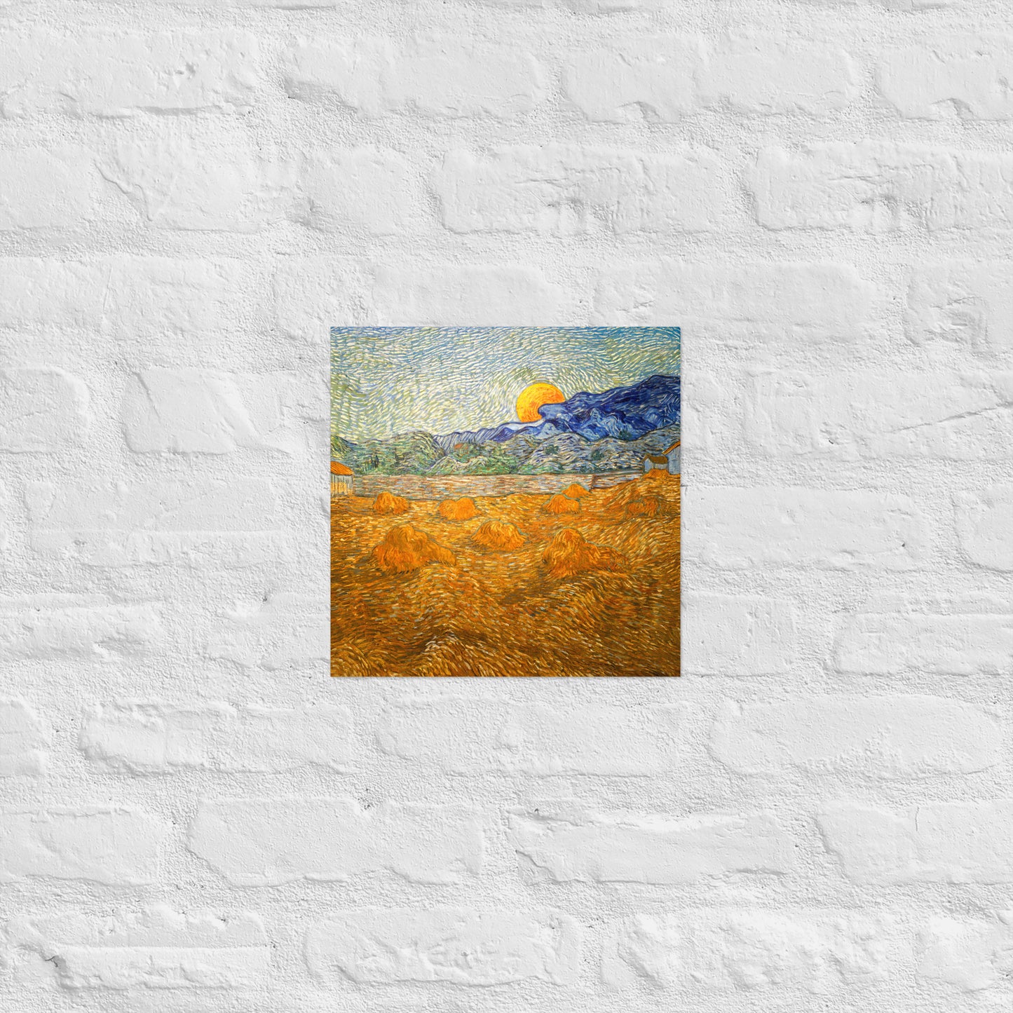 Van Gogh's 'Landscape with Wheat Sheaves and Rising Moon' on a 12"x12" unframed poster print on a white brick wall.
