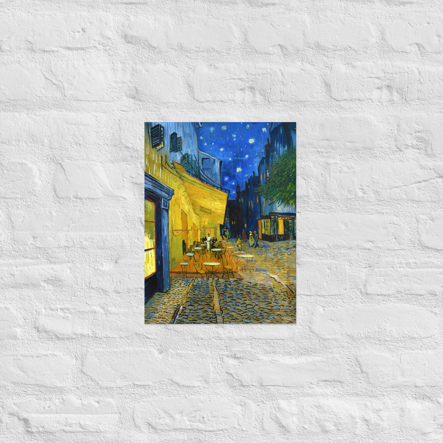 Van Gogh's 'Café Terrace at Night' on a 12"x16" unframed poster print on a white brick wall.