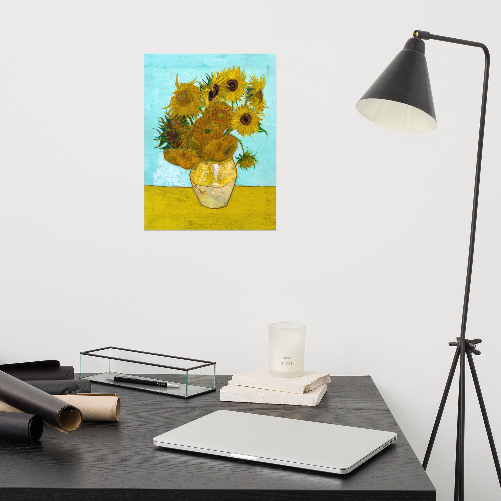 Van Gogh's 'Vase with Twelve Sunflowers' on a 12"x16" unframed poster print on a white wall above a modern office desk, lamp, and assorted desk items.