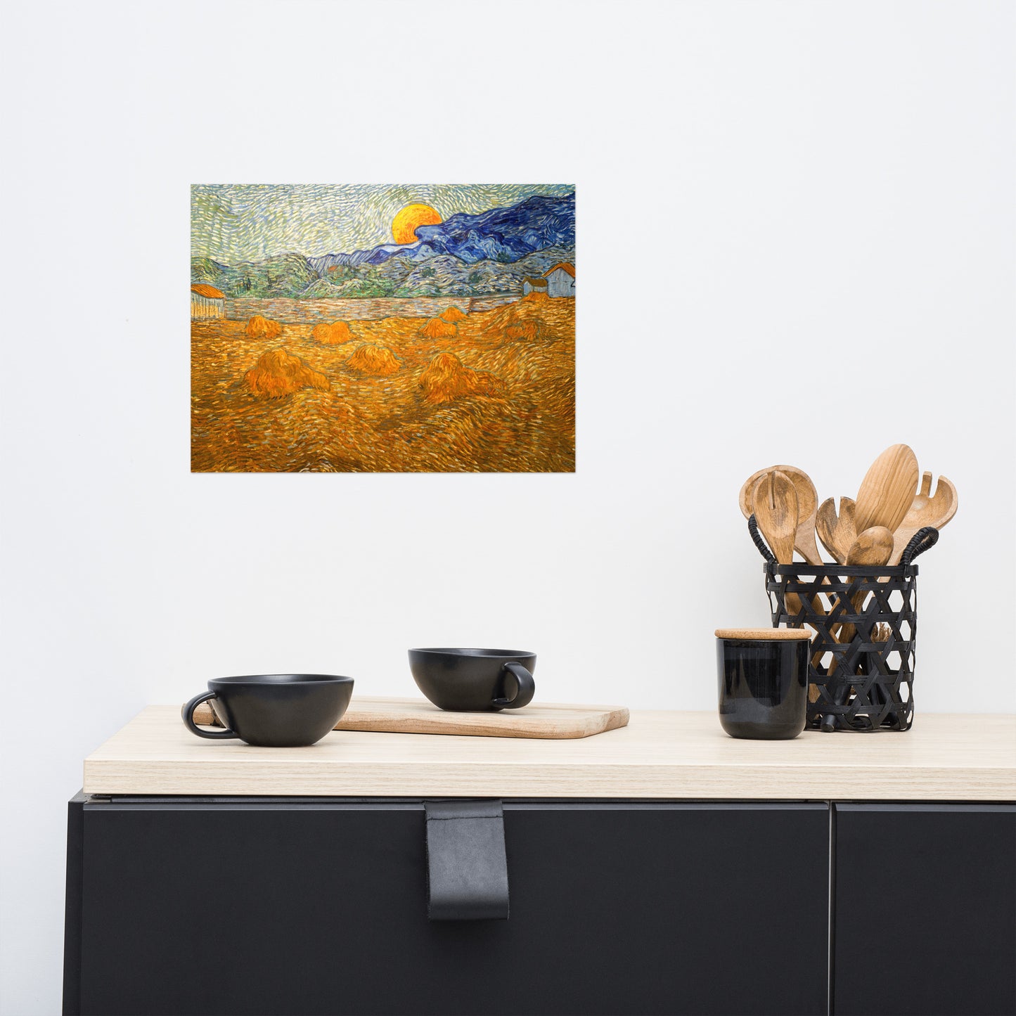 Van Gogh's 'Landscape with Wheat Sheaves and Rising Moon' on a 12"x16" unframed poster print on a white wall above a kitchen counter with cooking supplies.