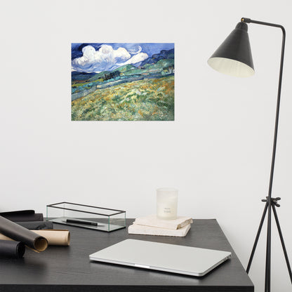 Van Gogh's 'Landscape from Saint-Rémy' on a 12"x16" unframed poster print on a white wall above a modern office desk, lamp, and assorted desk items.