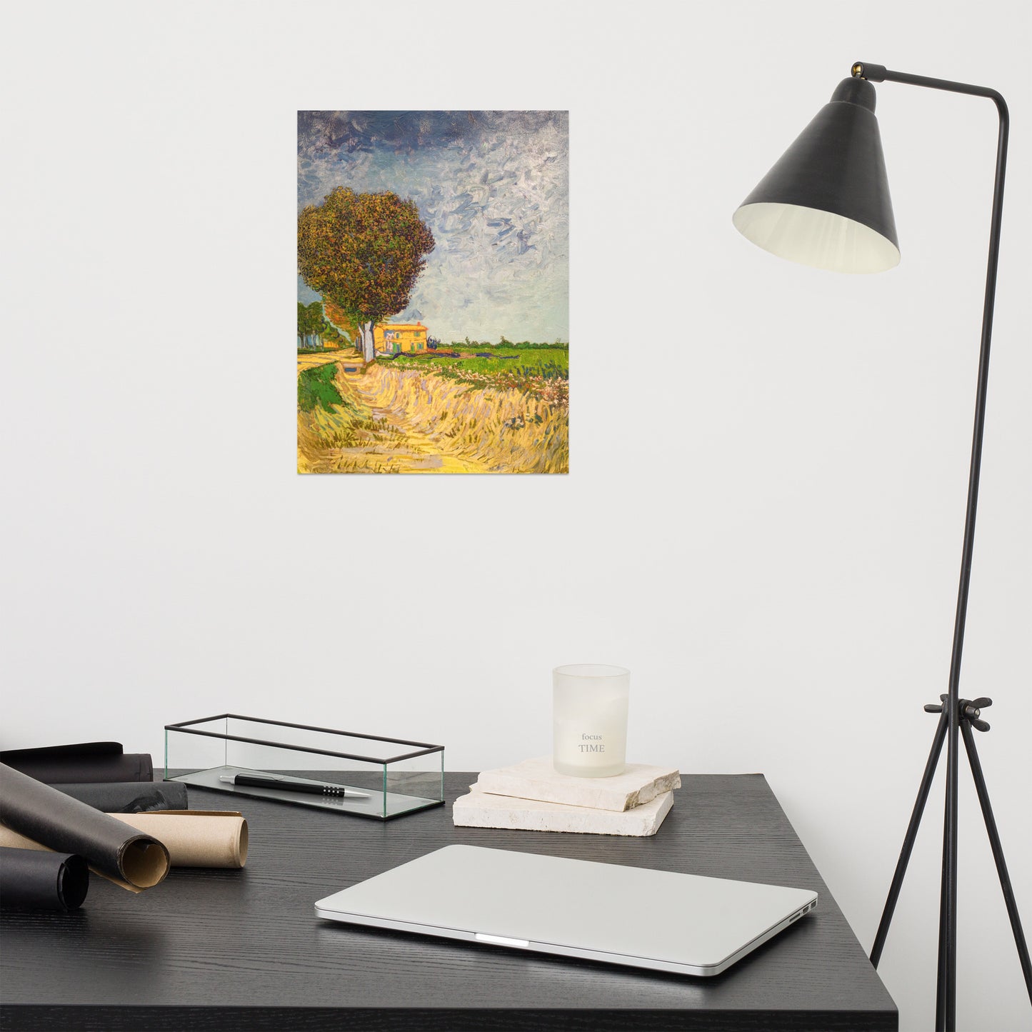 Van Gogh's 'A Lane near Arles' on a 12"x16" unframed poster print on a white wall above a modern office desk, lamp, and assorted desk items.