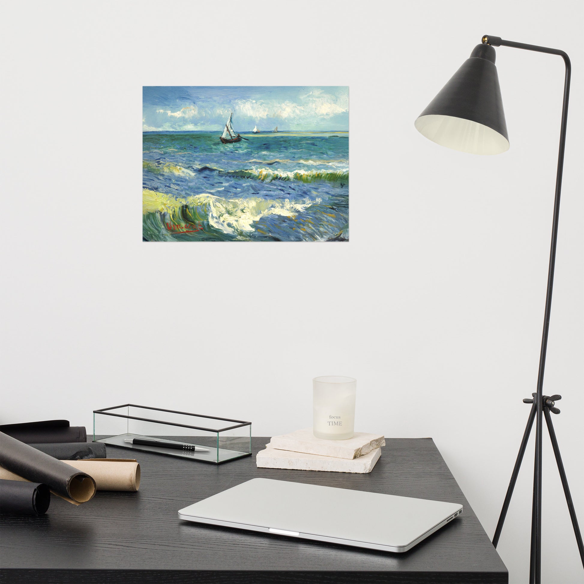 Van Gogh's 'The Sea at Les Saintes-Maries-de-la-Mer' on a 12"x16" unframed poster print on a white wall above a modern office desk, lamp, and assorted desk items.