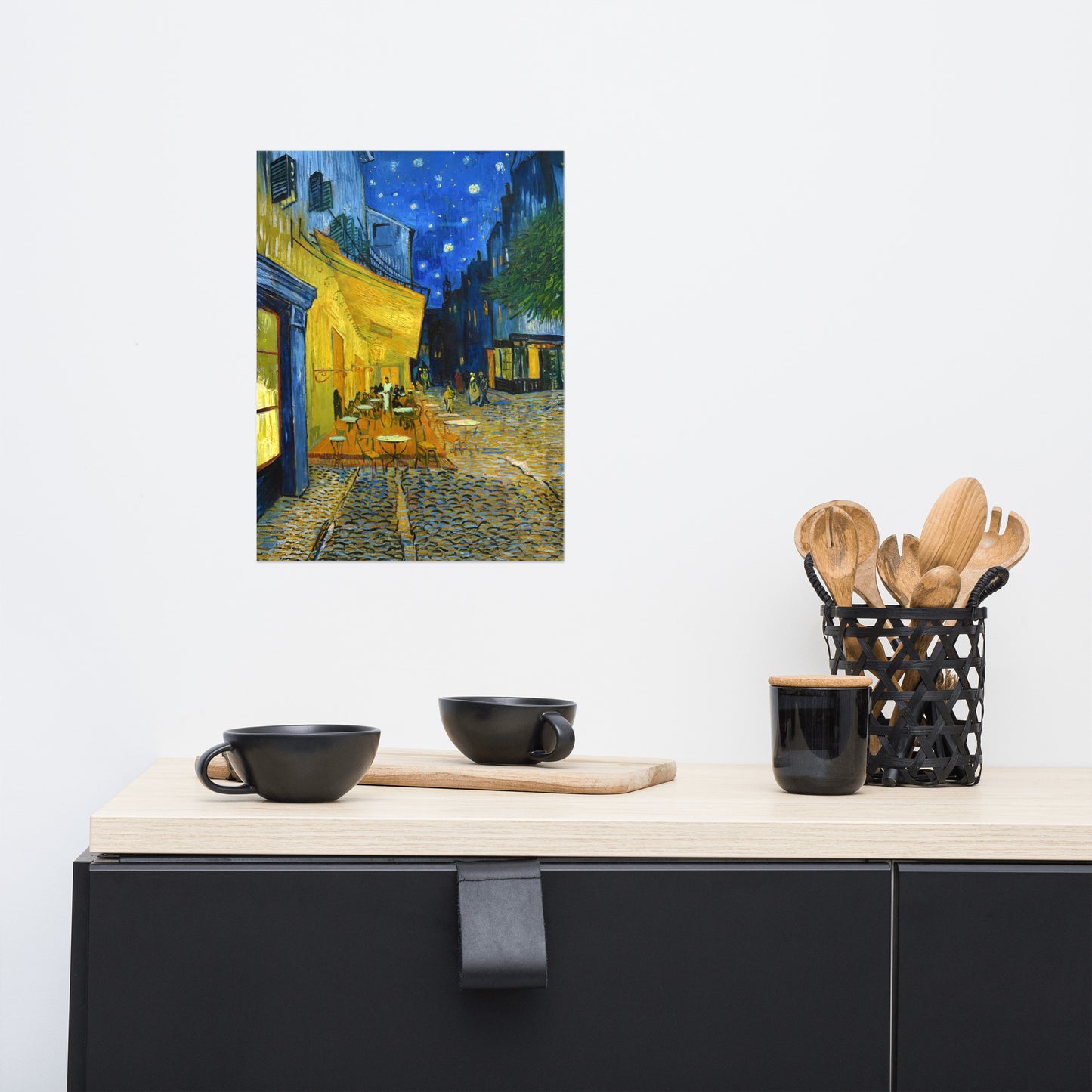 Van Gogh's 'Café Terrace at Night' on a 12"x16" unframed poster print on a white wall above a kitchen counter with cooking supplies.