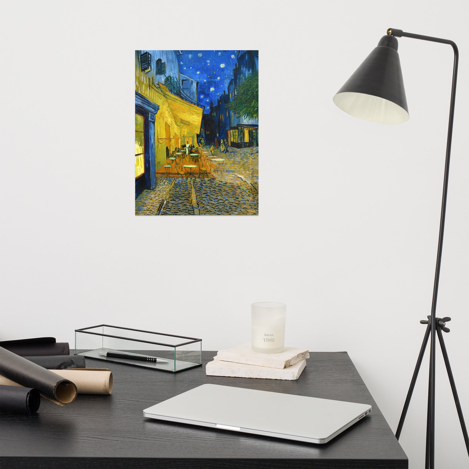 Van Gogh's 'Café Terrace at Night' on a 12"x16" unframed poster print on a white wall above a modern office desk, lamp, and assorted desk items.