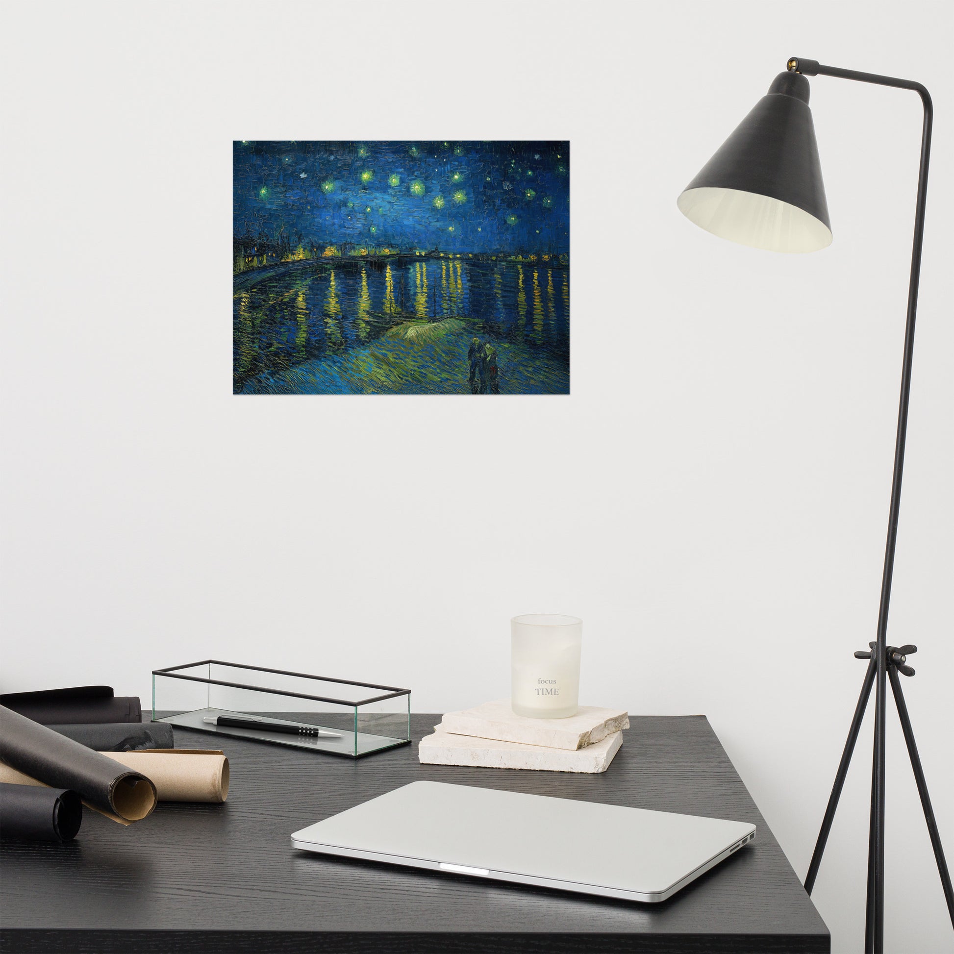 Van Gogh's 'Starry Night Over the Rhone' on a 12"x16" unframed poster print on a white wall above a modern office desk, lamp, and assorted desk items.
