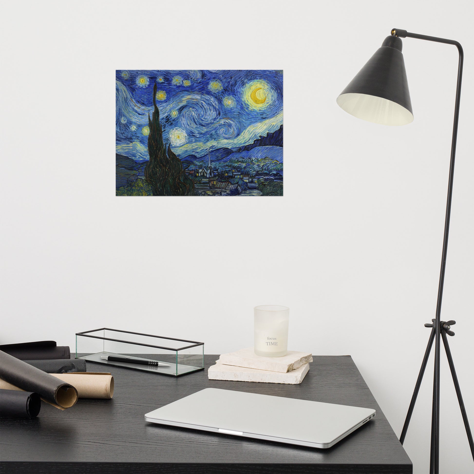 Van Gogh's 'Starry Night' on a 12"x16" unframed poster print on a white wall above a modern office desk, lamp, and assorted desk items.
