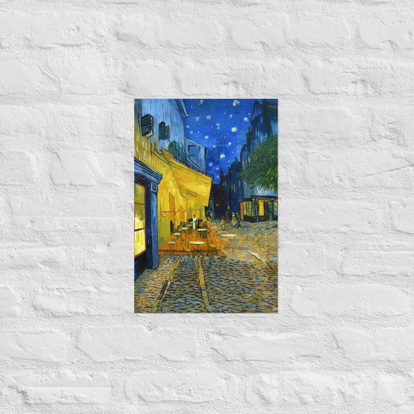 Van Gogh's 'Café Terrace at Night' on a 12"x18" unframed poster print on a white brick wall.