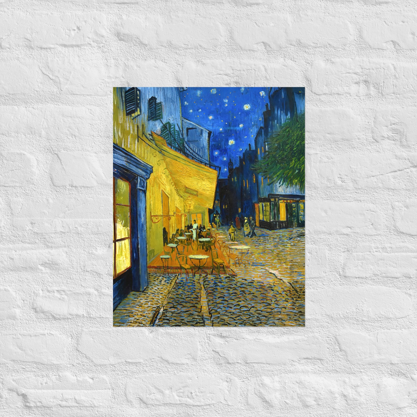 Van Gogh's 'Café Terrace at Night' on a 16"x20" unframed poster print on a white brick wall.