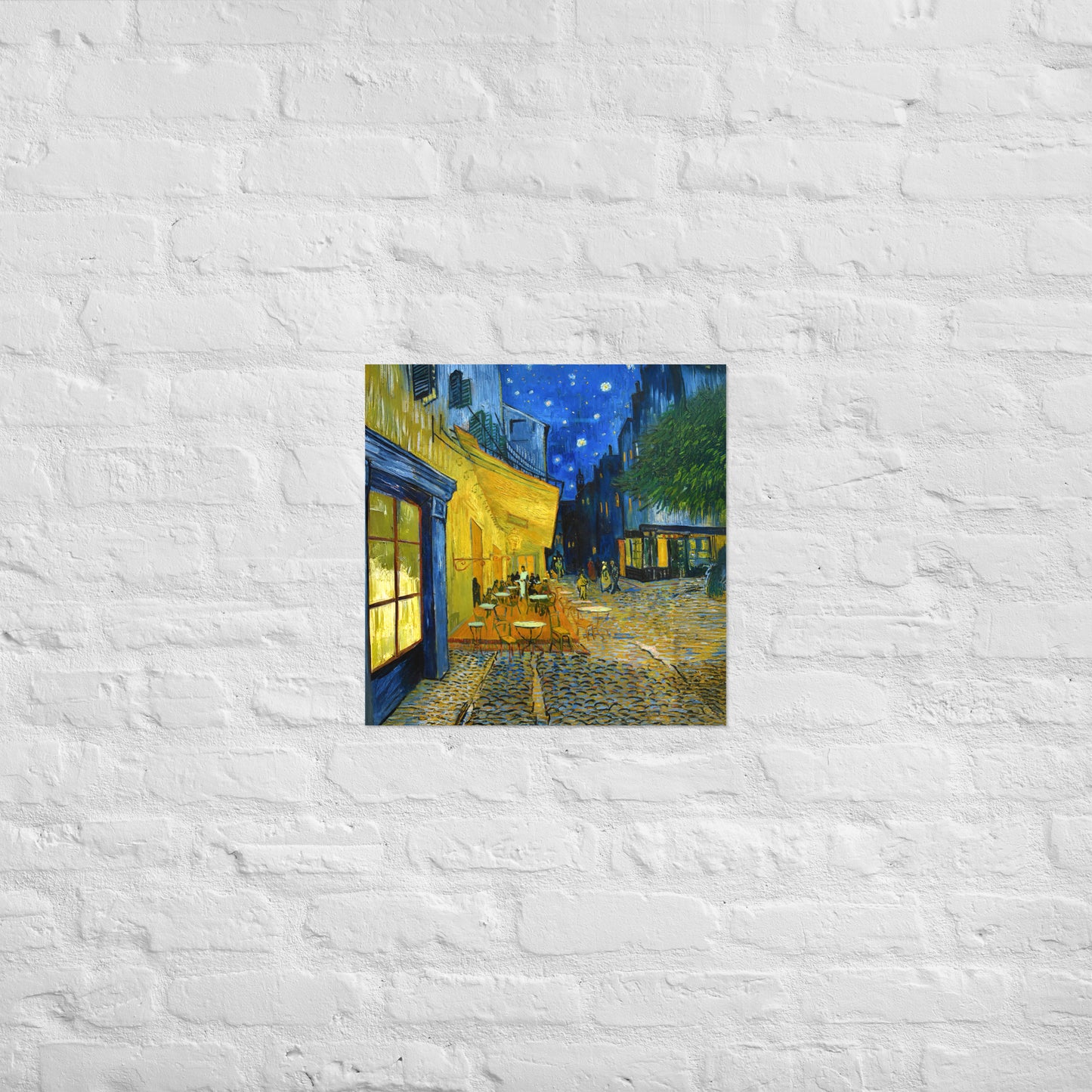 Van Gogh's 'Café Terrace at Night' on a 18"x18" unframed poster print on a white brick wall.