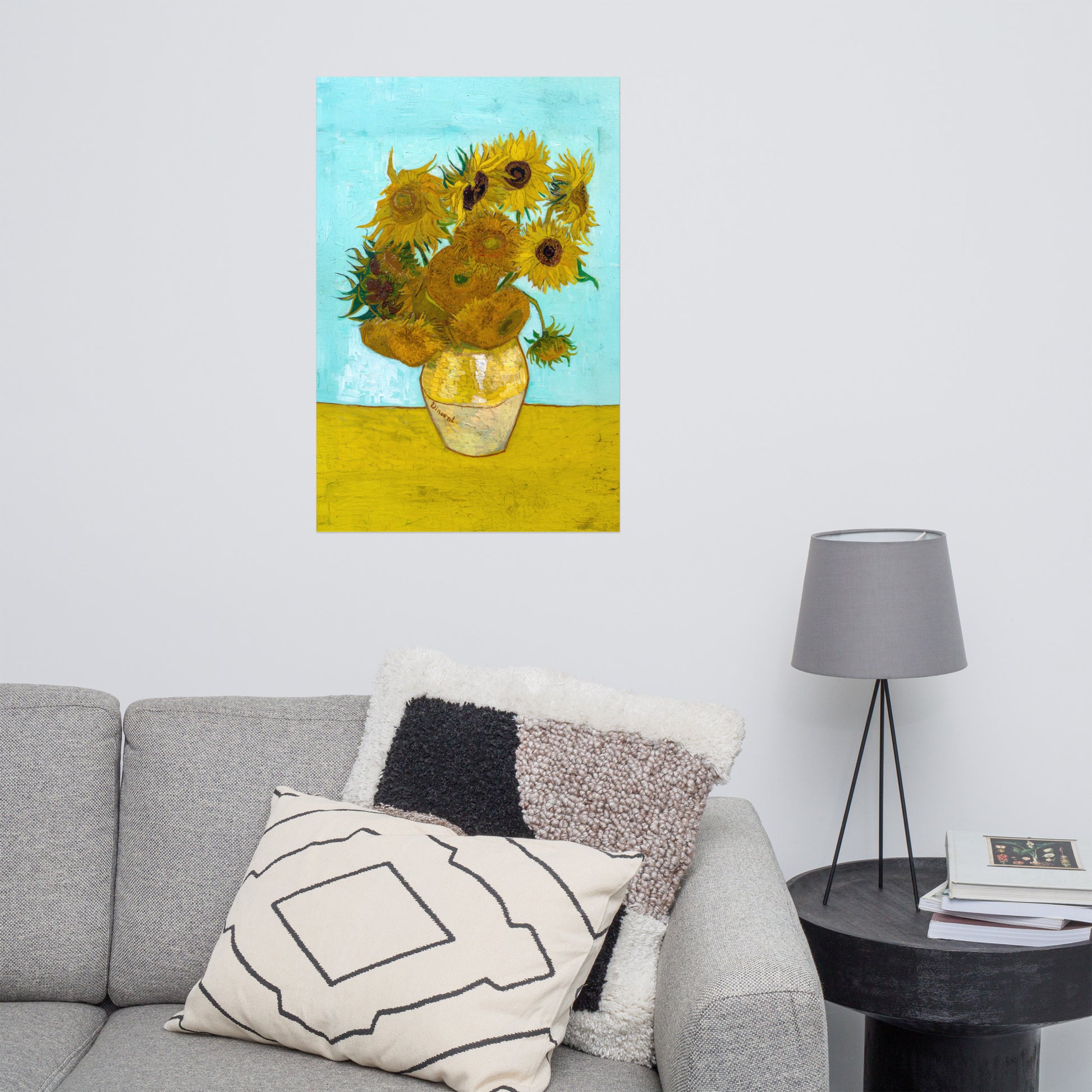Van Gogh's 'Vase with Twelve Sunflowers' on a 24"x36" unframed poster print on a white wall above a gray sofa with throw pillows and side table with a lamp.
