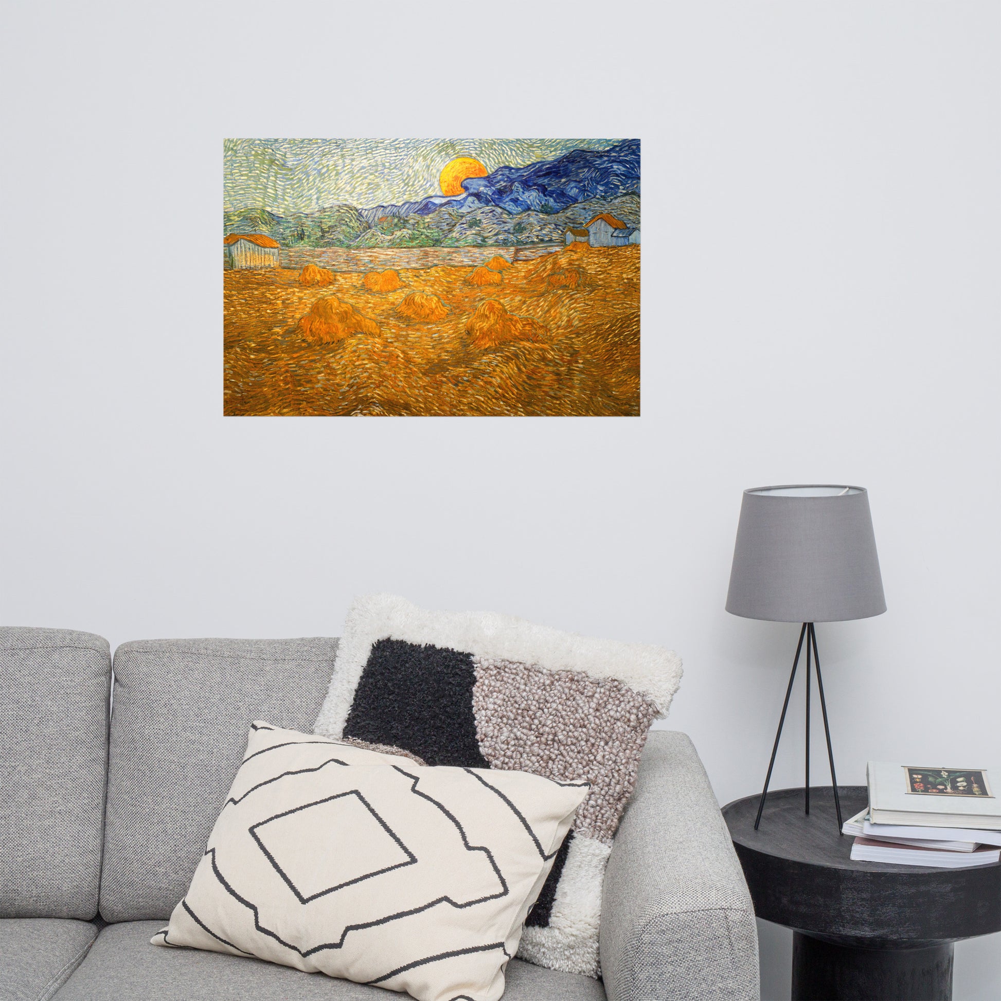Van Gogh's 'Landscape with Wheat Sheaves and Rising Moon' on a 24"x36" unframed poster print on a white wall above a gray sofa with throw pillows and side table with a lamp.