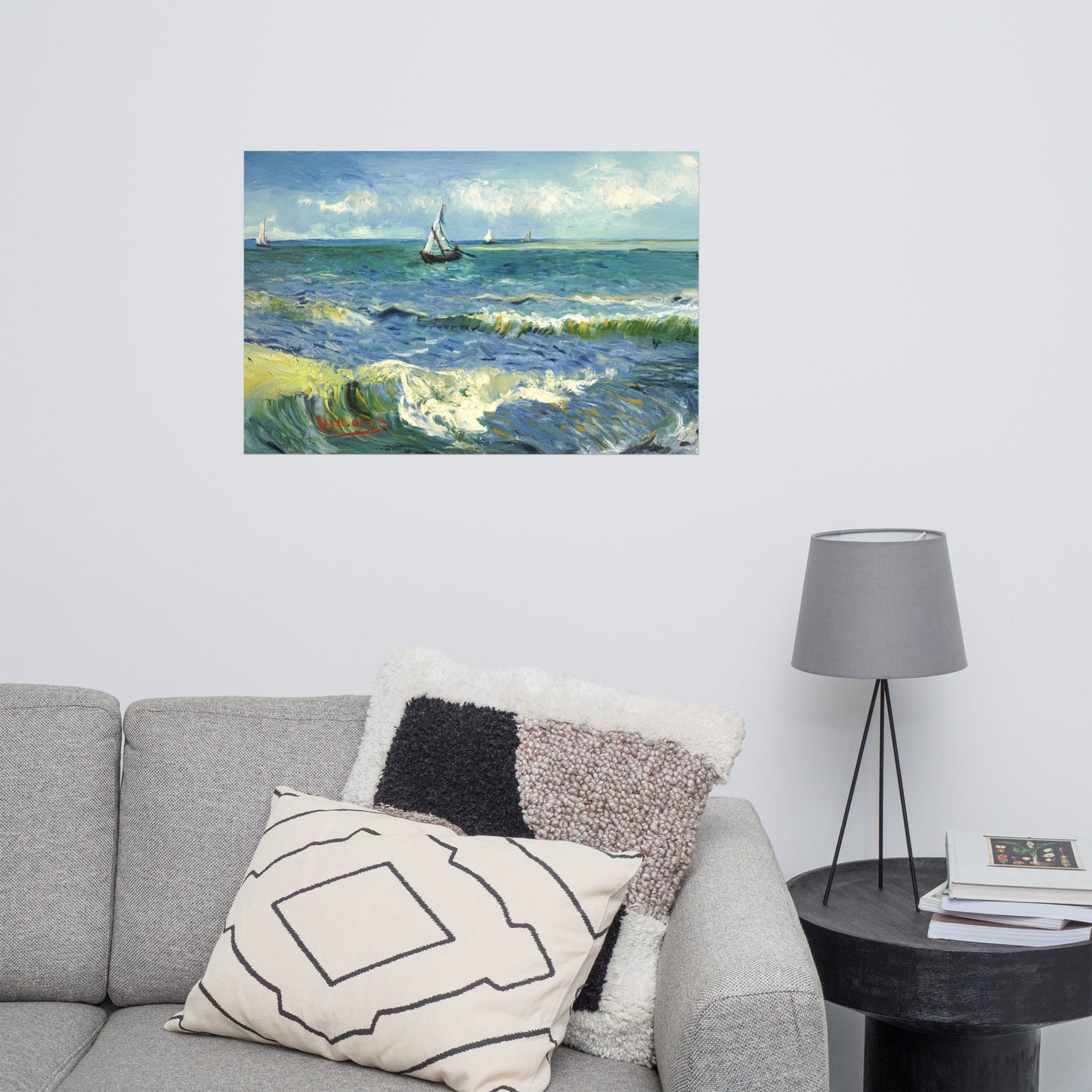 Van Gogh's 'The Sea at Les Saintes-Maries-de-la-Mer' on a 24"x36" unframed poster print on a white wall above a gray sofa with throw pillows and side table with a lamp.
