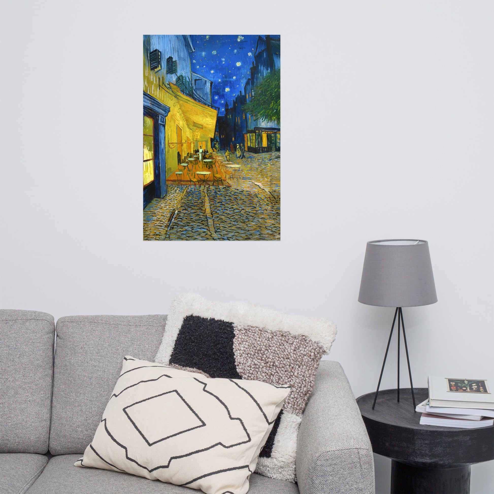Van Gogh's 'Café Terrace at Night' on a 24"x36" unframed poster print on a white wall above a gray sofa with throw pillows and side table with a lamp.