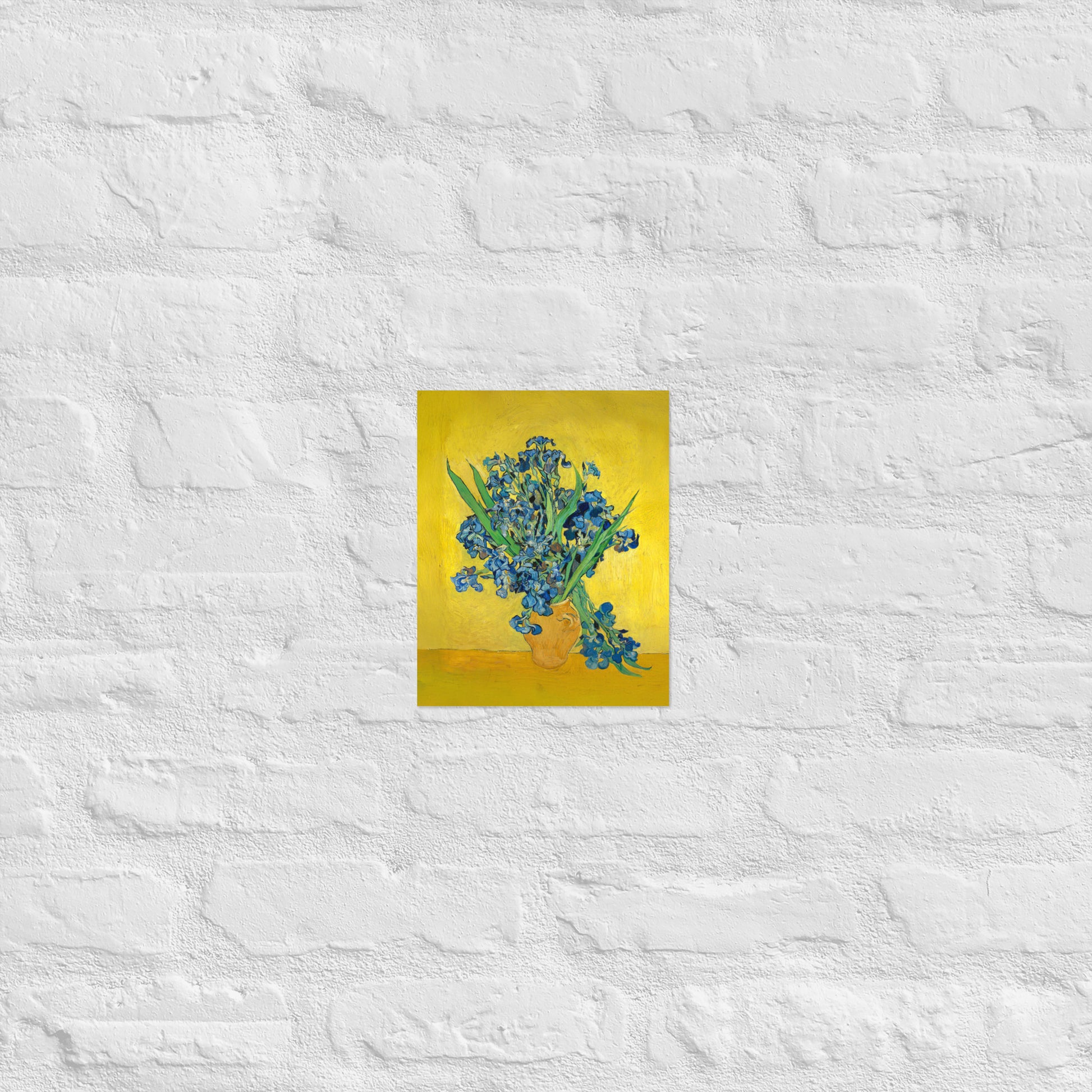 Van Gogh's 'Vase with Irises Against a Yellow Background' on a 8"x10" unframed poster print on a white brick wall.