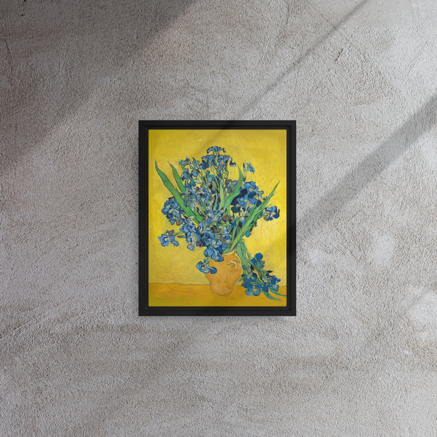 Van Gogh's 'Vase with Irises Against a Yellow Background' on a 11"x14" black framed canvas print on a textured gray wall.