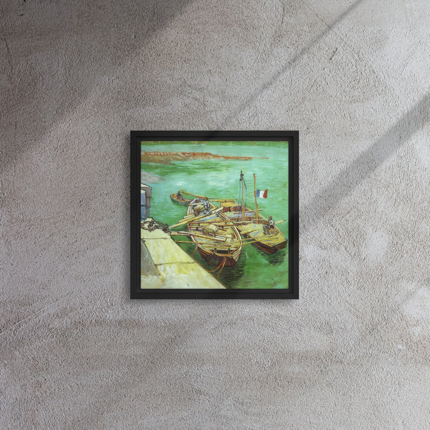 Van Gogh's 'Quay with Men Unloading Sand Barges' on a 12"x12" black framed canvas print on a textured gray wall.