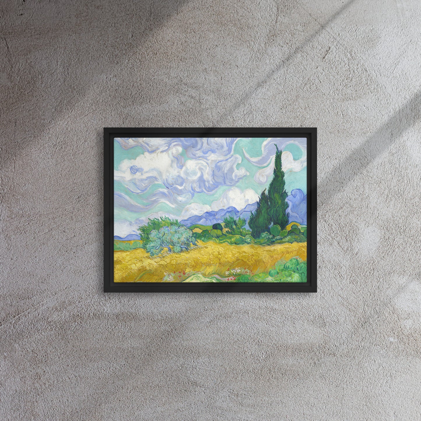 Van Gogh's 'Wheat Field with Cypresses' on a 12"x16" black framed canvas print on a textured gray wall.