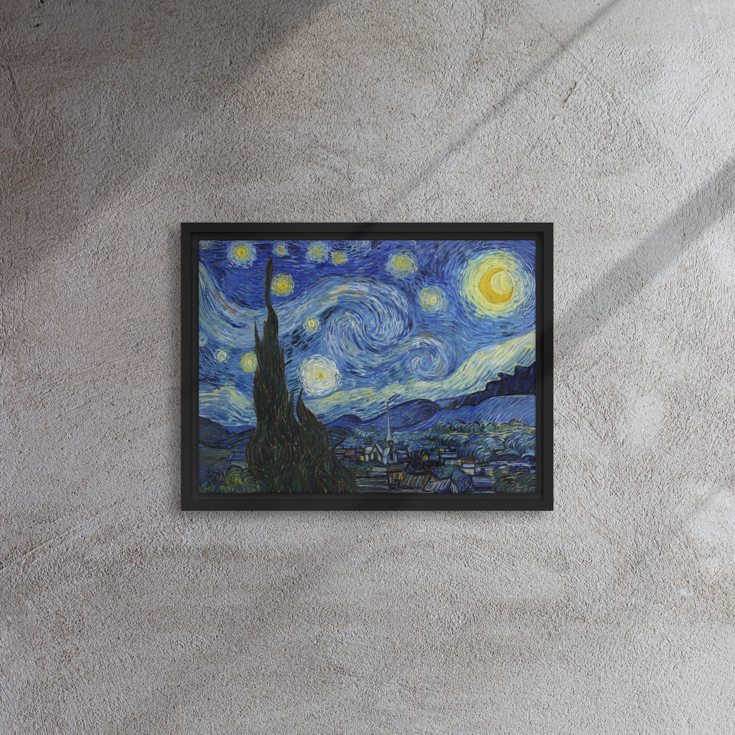 Van Gogh's 'Starry Night' on a 12"x16" black framed canvas print on a textured gray wall.