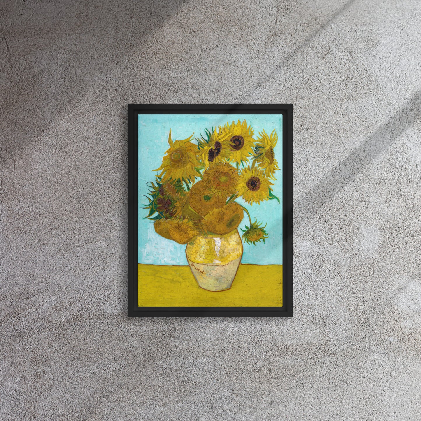 Van Gogh's 'Vase with Twelve Sunflowers' on a 12"x16" black framed canvas print on a textured gray wall.