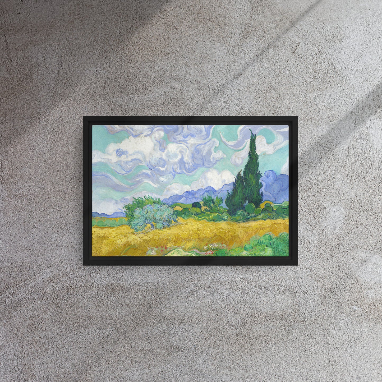 Van Gogh's 'Wheat Field with Cypresses' on a 12"x18" black framed canvas print on a textured gray wall.
