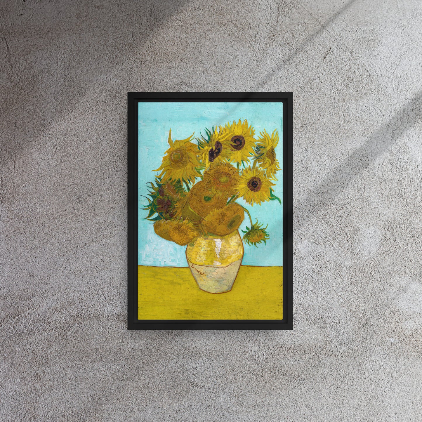 Van Gogh's 'Vase with Twelve Sunflowers' on a 12"x18" black framed canvas print on a textured gray wall.