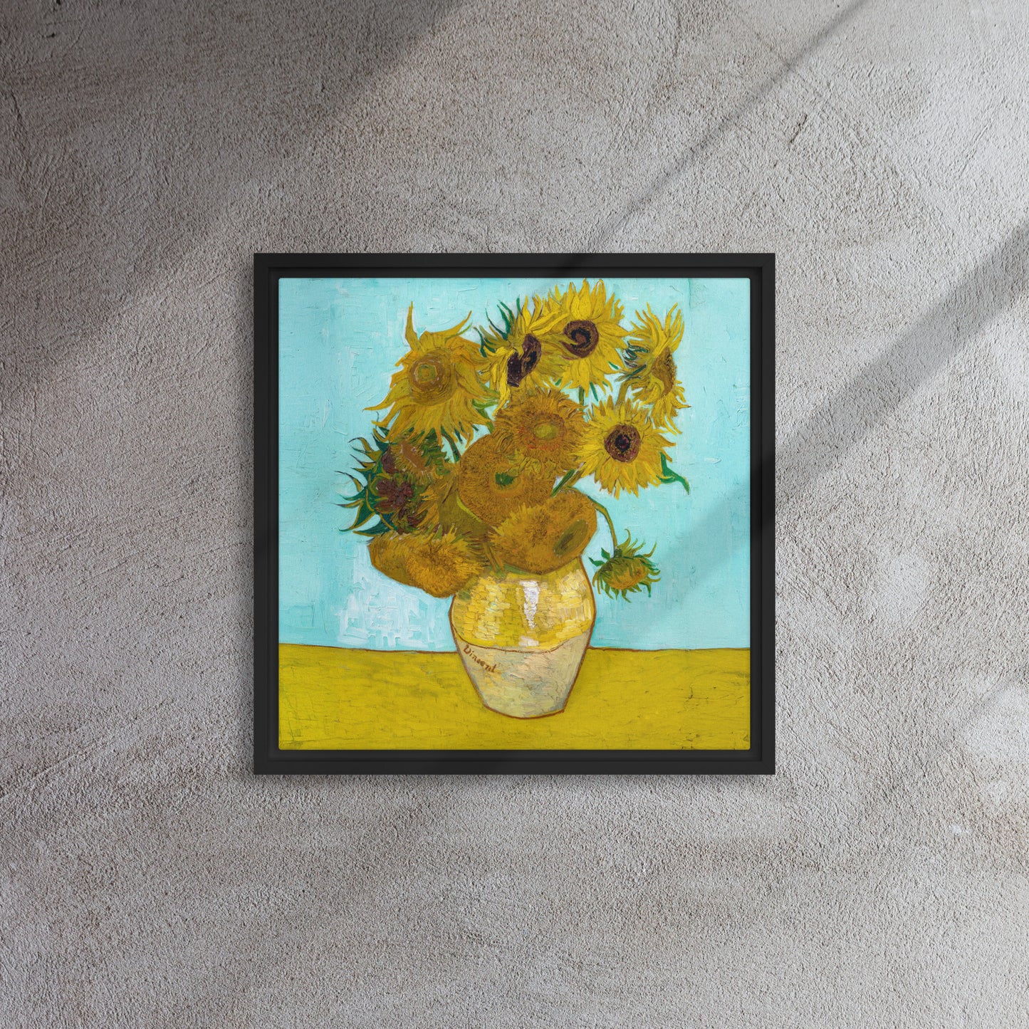 Van Gogh's 'Vase with Twelve Sunflowers' on a 16"x16" black framed canvas print on a textured gray wall.