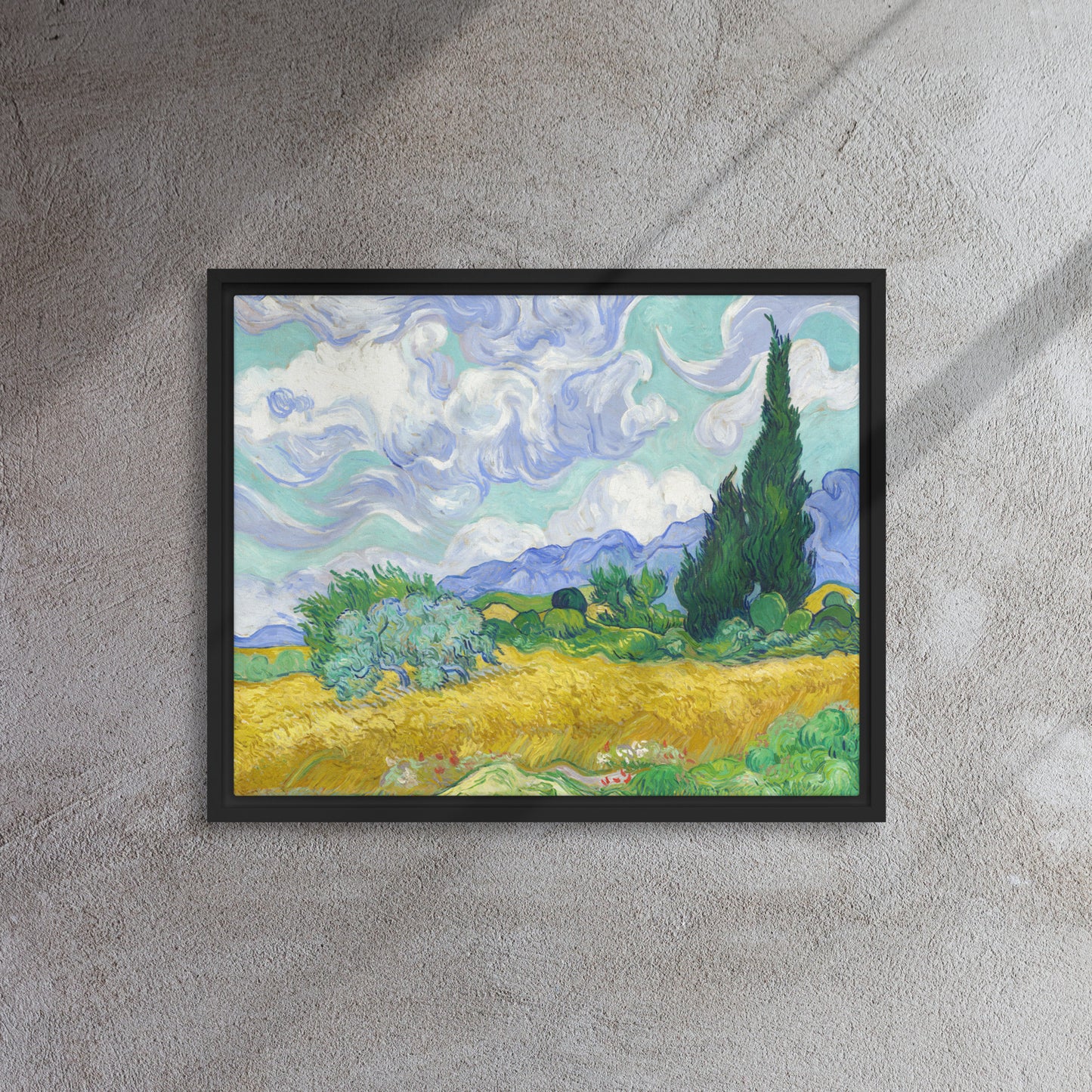 Van Gogh's 'Wheat Field with Cypresses' on a 16"x20" black framed canvas print on a textured gray wall.