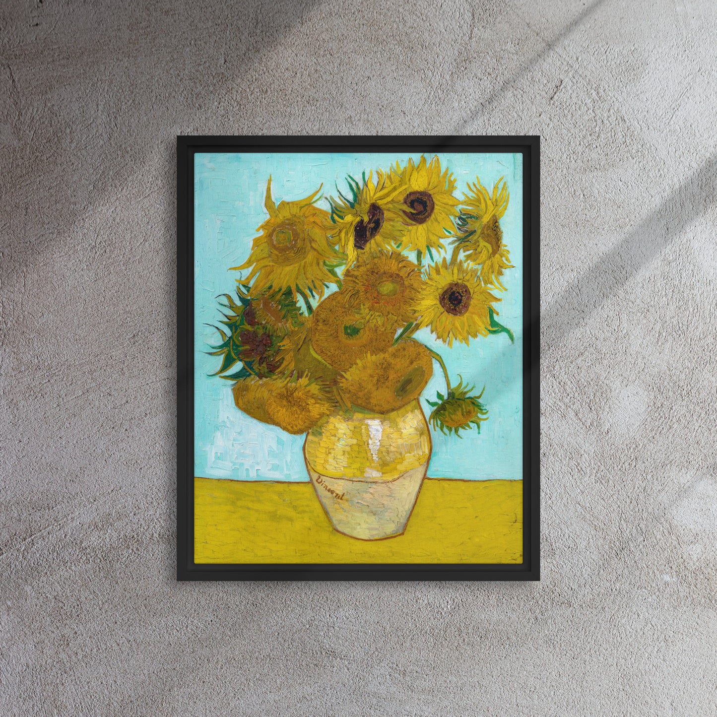 Van Gogh's 'Vase with Twelve Sunflowers' on a 16"x20" black framed canvas print on a textured gray wall.