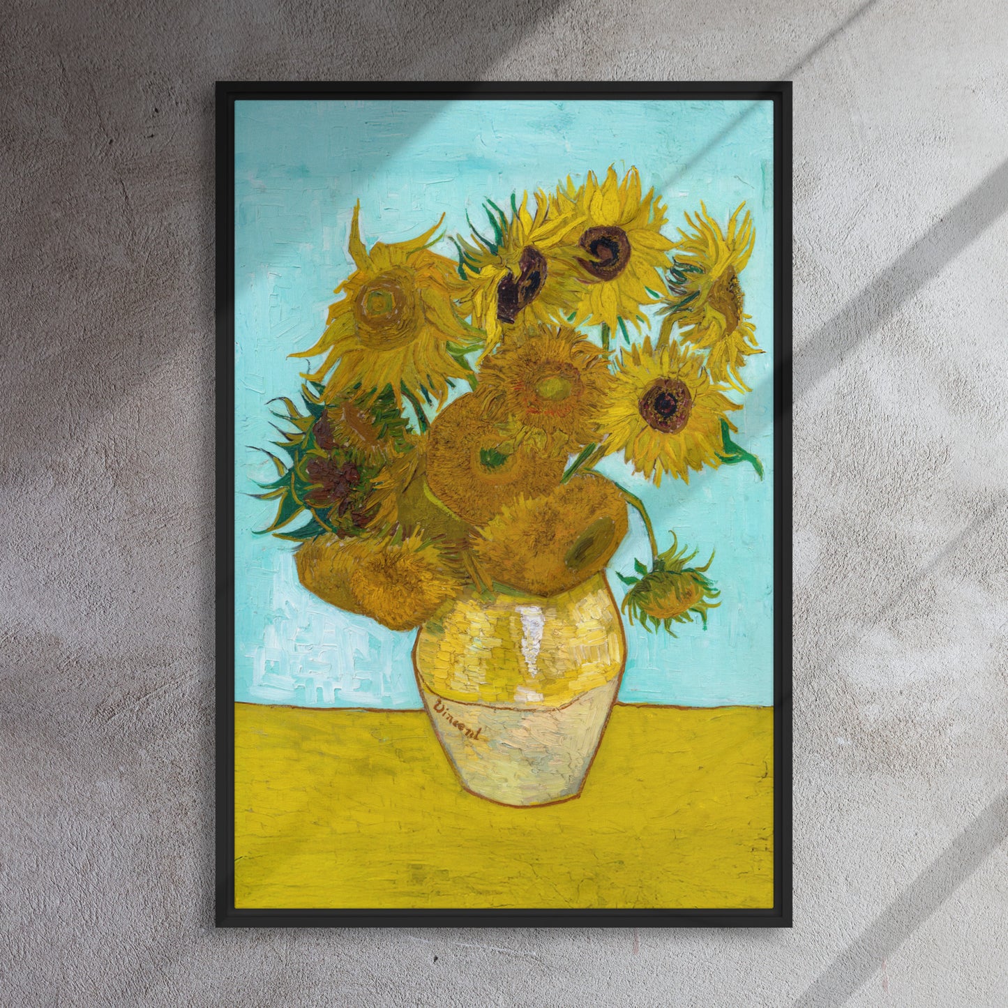 Van Gogh's 'Vase with Twelve Sunflowers' on a 24"x36" black framed canvas print on a textured gray wall.