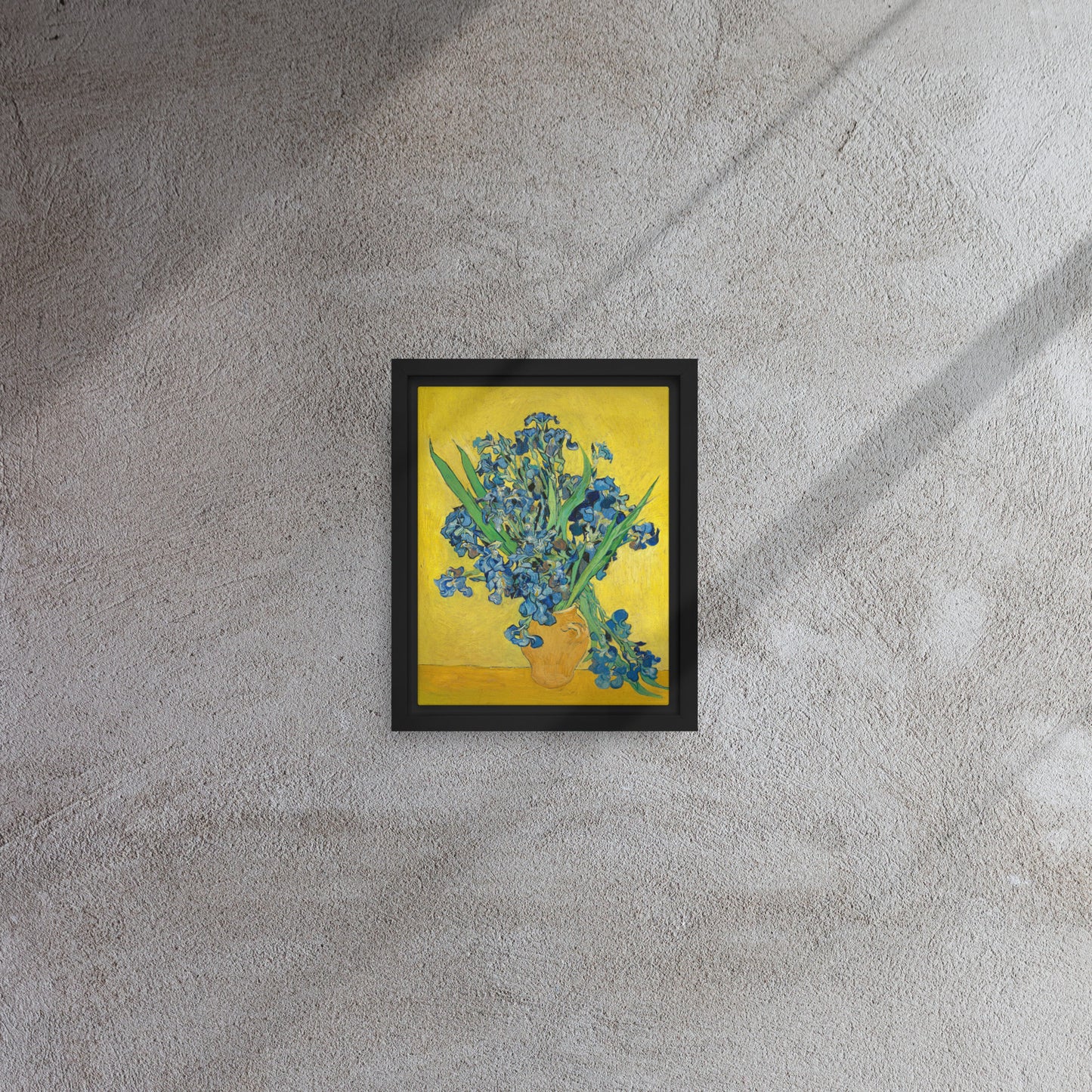 Van Gogh's 'Vase with Irises Against a Yellow Background' on a 8"x10" black framed canvas print on a textured gray wall.