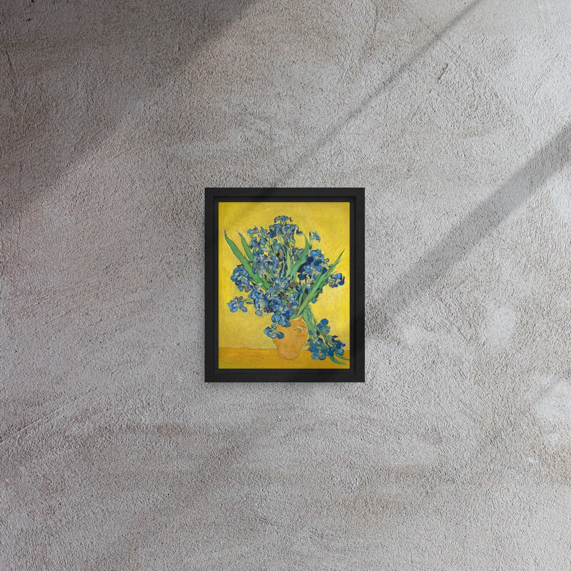 Van Gogh's 'Vase with Irises Against a Yellow Background' on a 8"x10" black framed canvas print on a textured gray wall.