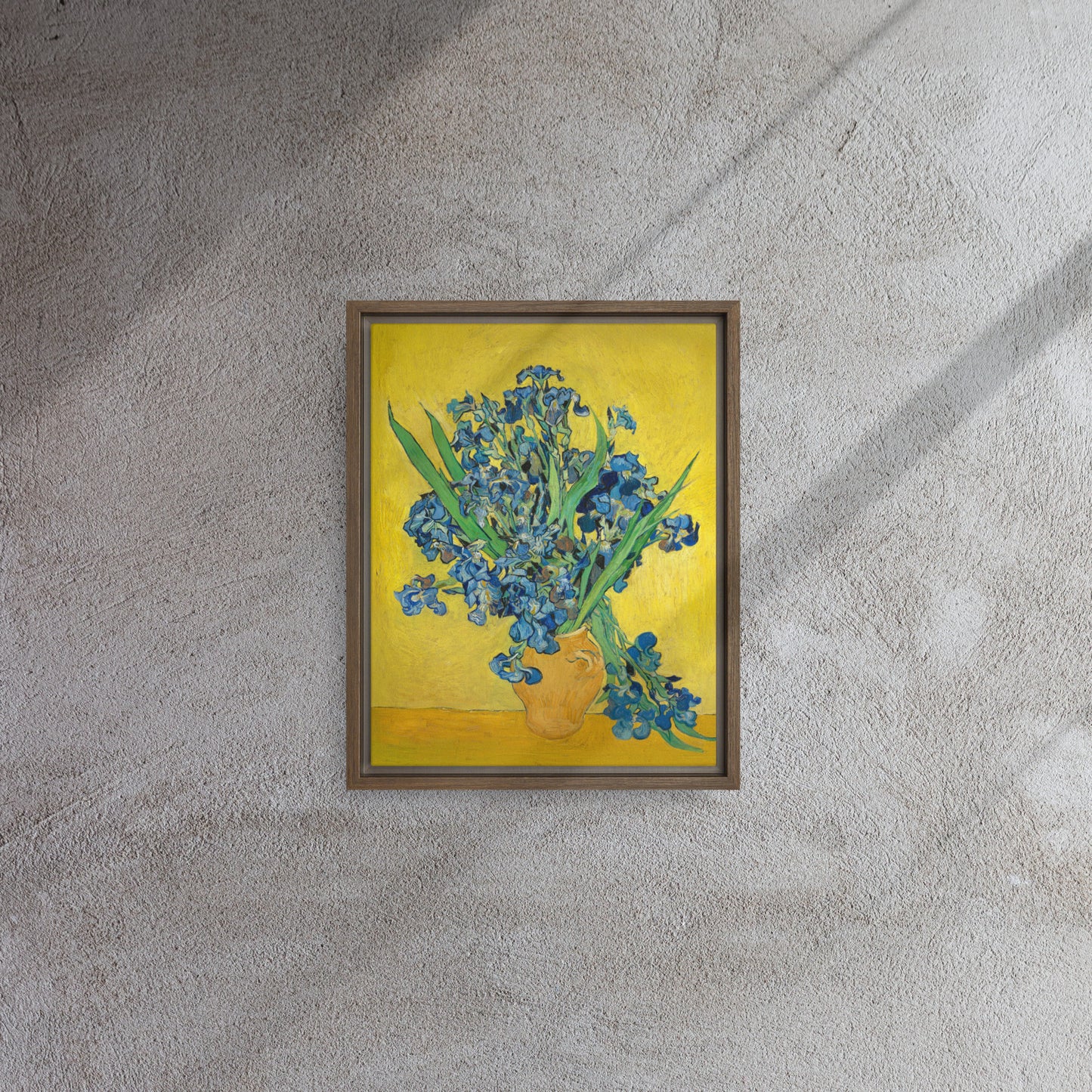 Van Gogh's 'Vase with Irises Against a Yellow Background' on a 11"x14" brown framed canvas print on a textured gray wall.