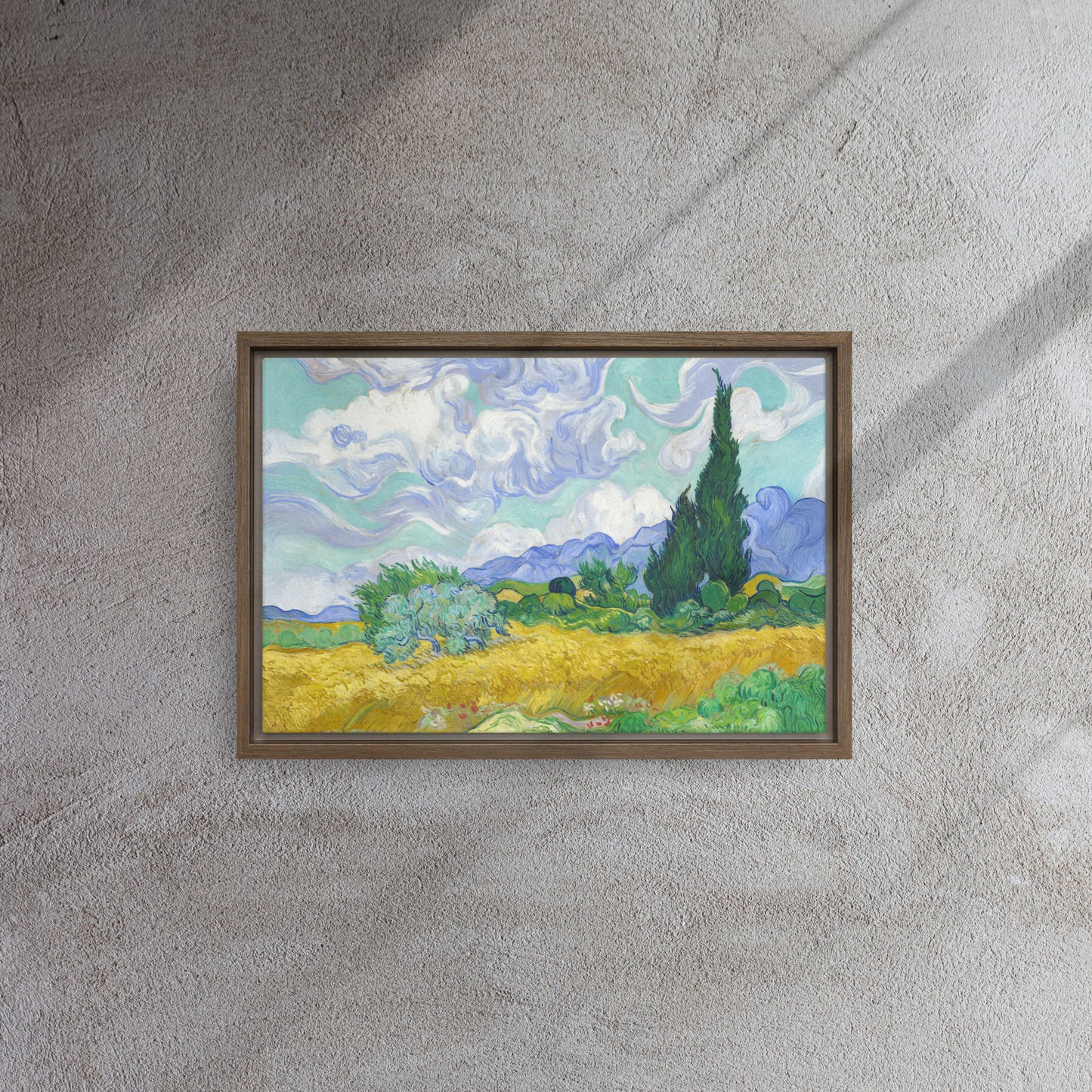 Van Gogh's 'Wheat Field with Cypresses' on a 12"x18" brown framed canvas print on a textured gray wall.